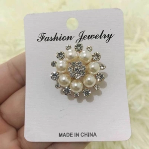 Detailed view of elegant gold-tone flower brooch with white pearls and sparkling rhinestones