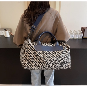 Dettaglio della borsa da viaggio con stampa geometrica, logo Moda Bag e manici in pelle blu
