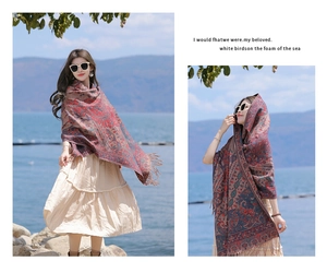 Close-up of red paisley shawl with fringe detailing worn by a model near a scenic lake