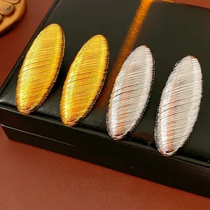 Textured metallic oval hoop earrings in polished gold and silver finishes