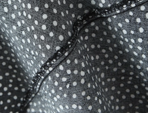 Detail of polka dot fabric showing professional overlock stitching and soft chiffon texture