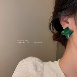 Elegant dark green geometric enamel earrings with vintage metallic texture worn by a model