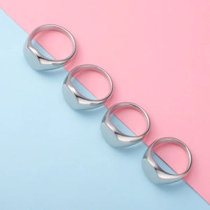 Detailed view of four polished silver oval signet rings on a pastel split background