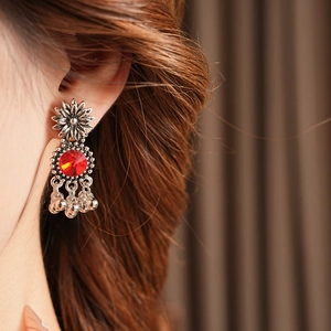 Close-up of vintage flower earrings with red crystal stone and small bell pendants
