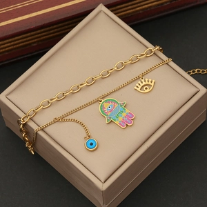 Detail of double-layer gold chain with Fatima hand and evil eye charms on jewelry box