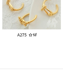 Close-up of interlocking C-shape gold earrings with zircon inlay on white lace