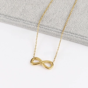 Primer plano de un collar con colgante de símbolo de infinito dorado y cadena fina