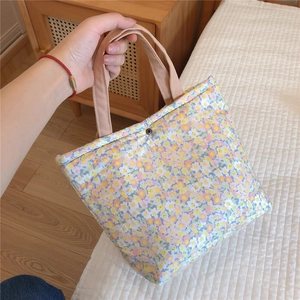Detailed view of floral cotton tote bag with khaki straps and bronze snap button closure