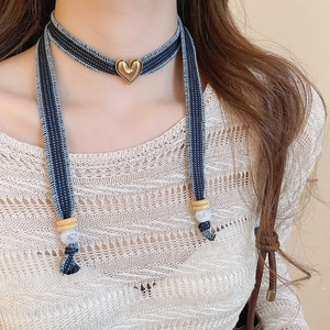 Detail of denim fabric choker with golden heart pendant and mixed bead accents