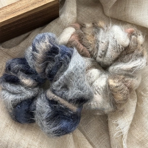 Gros plan de chouchous surdimensionnés en laine douce aux tons bleu-gris et beige