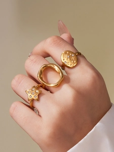 Detailed close-up of three gold-plated stainless steel rings with star and wave designs