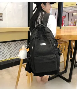 Détail du sac à dos noir gaufré avec compartiments zippés et breloque lapin en peluche