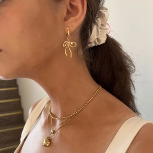 Golden bow earrings and layered heart necklace set worn by a model for a sweet look