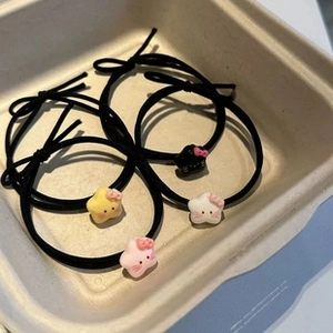 Detail of four black elastic hair ties featuring colorful resin star pendants in a tray