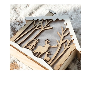 Detail of wooden Christmas house featuring laser-cut deer silhouette and snow-capped roof