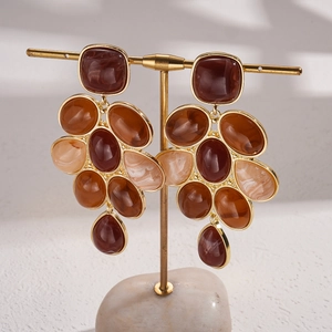 Detail view of retro geometric resin cluster earrings on a gold T-stand display