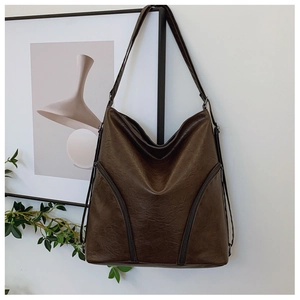 Detailed texture of a dark brown faux leather shoulder bag with decorative dual zippers