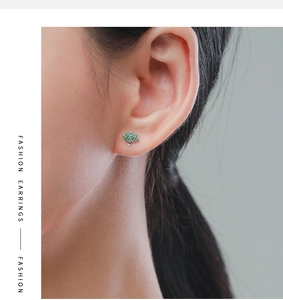 Close-up of a s925 silver green tree stud earring worn by a model in a fashion style