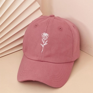 Detailed close-up of white rose embroidery on a pink cotton baseball cap with curved brim