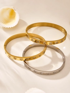 Macro detail of three gold and silver bangles with heart-shaped crystal patterns
