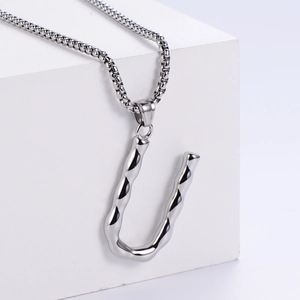Détail macro du pendentif lettre U argenté avec texture de métal liquide irrégulier