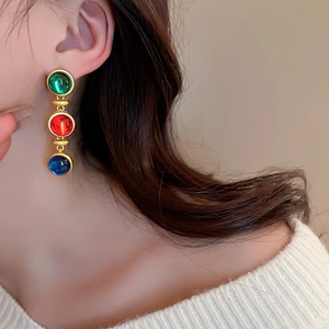 Détail de boucles d'oreilles vintage avec triple pierre précieuse et monture dorée