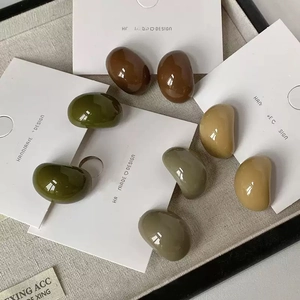 Detailed view of four pairs of smooth pebble-shaped acrylic earrings in earthy tones