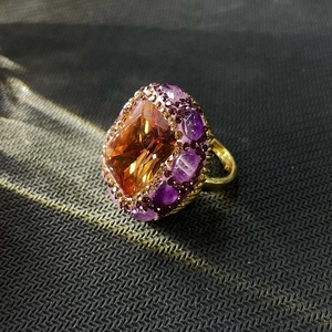 Detail of vintage ring featuring large orange gemstone surrounded by purple crystals