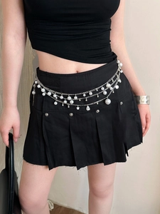 Detailed view of silver layered waist chain with pearls and star charms on a black skirt