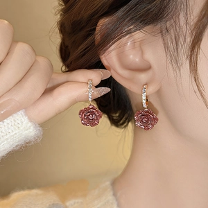 Détail du mannequin portant une boucle d'oreille rose rouge et clous dorés sertis de diamants