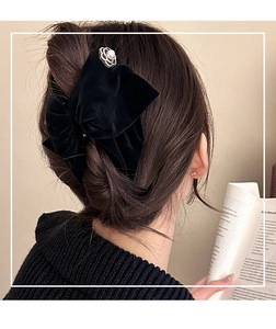 Close-up of a velvet bow hair claw with pearl camellia flower on model's hair