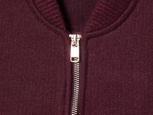 Dettaglio della zip in metallo dorato sulla giacca bordeaux in lana morbida