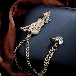 Macro shot of gold violin brooch with sparkling rhinestones and double metal chains