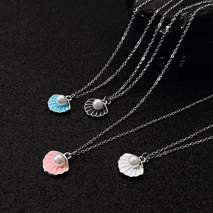 Macro shot of colorful shell necklaces with central pearls on dark textured background