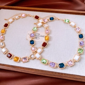 Detail of vintage gold necklace with colorful rectangular gemstones and crystal accents