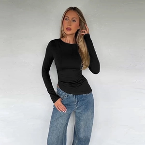 Detail of slim-fit black long sleeve top with an asymmetrical hem on female model