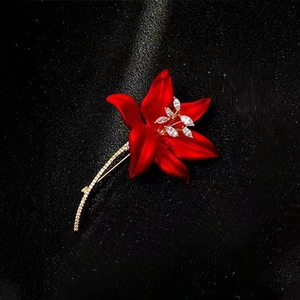Close-up of red velvet lily brooch with sparkling crystal stamens on black background