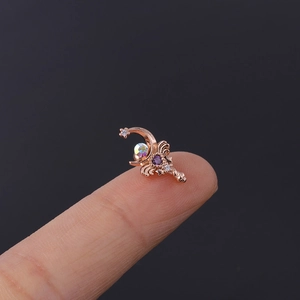 Macro detail of rose gold moon and star cartilage stud with colorful zircon on fingertip