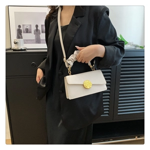Détail du sac à rabat blanc avec boucle dorée et poignée plissée style nuage chic