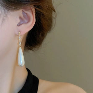 Close-up of elegant gold-plated drop pearl earrings with zircon inlay on model
