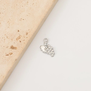 Macro detail of a silver stainless steel grape pendant on a textured stone base