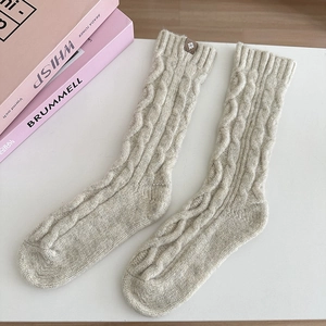 Detailed knit texture of cable knit wool socks in beige with leather tag detail