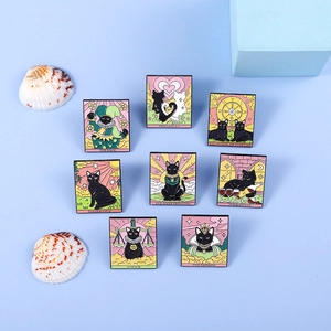 Nahaufnahme von 8 Emaille-Pins mit schwarzer Katze und Tarot-Motiven wie Der Narr
