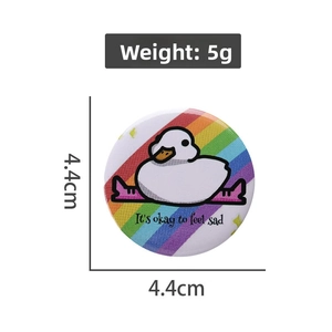 Detail view of a 4.4cm round tinplate badge featuring a cartoon duck and emotional quote