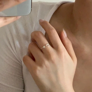 Detail of gold heart open ring with square zircon stone worn on finger