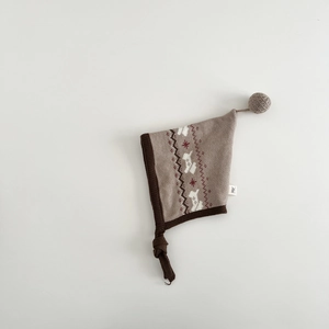 Detail of baby knitted earflap hat with Nordic jacquard pattern and pompom top