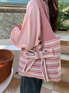 Detail of a large pink and white striped knit tote bag with a cute oversized bow decoration
