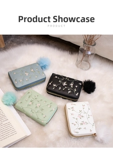 Flat lay of four colorful floral embroidered zip wallets with soft pompom charms on a rug