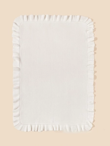 Macro detail of white knitted baby blanket featuring delicate ruffled edges and fine texture