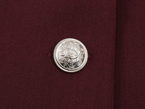 Detailed macro shot of vintage silver heraldic buttons on deep red tweed jacket fabric